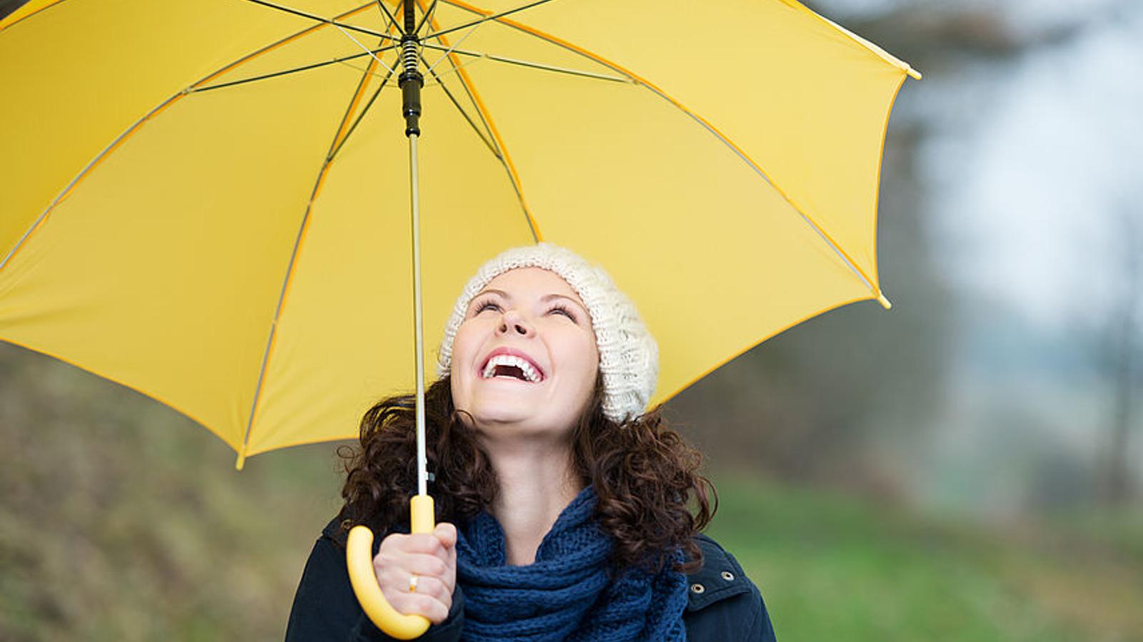 Frau mit gelben Regenschirm lacht. 