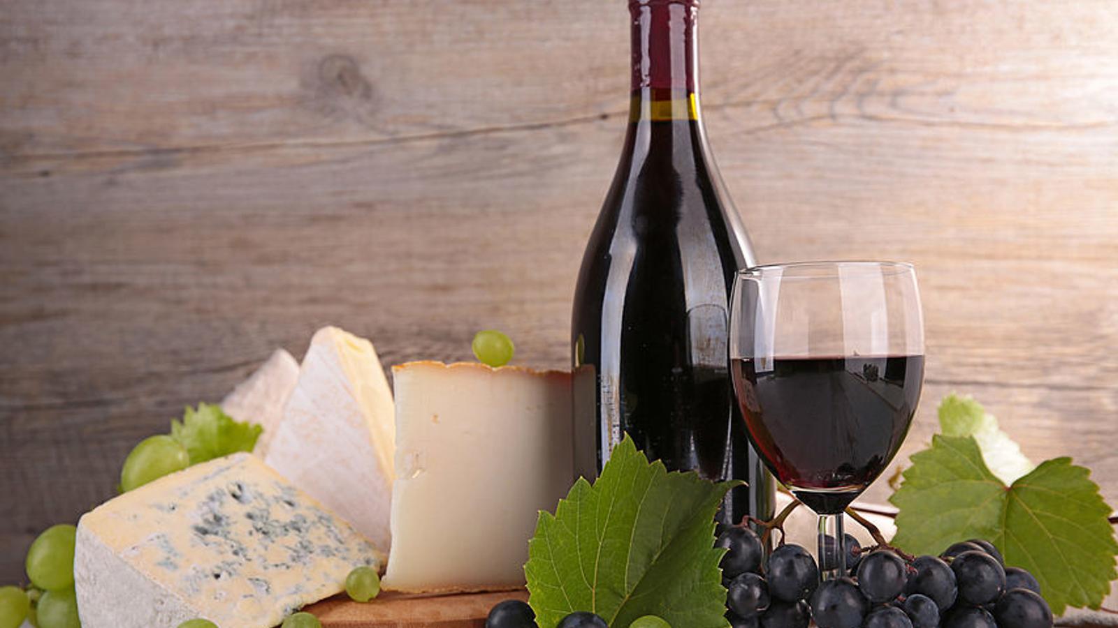 Rotweinflasche, Rotweinglas und Käse auf einem Tisch