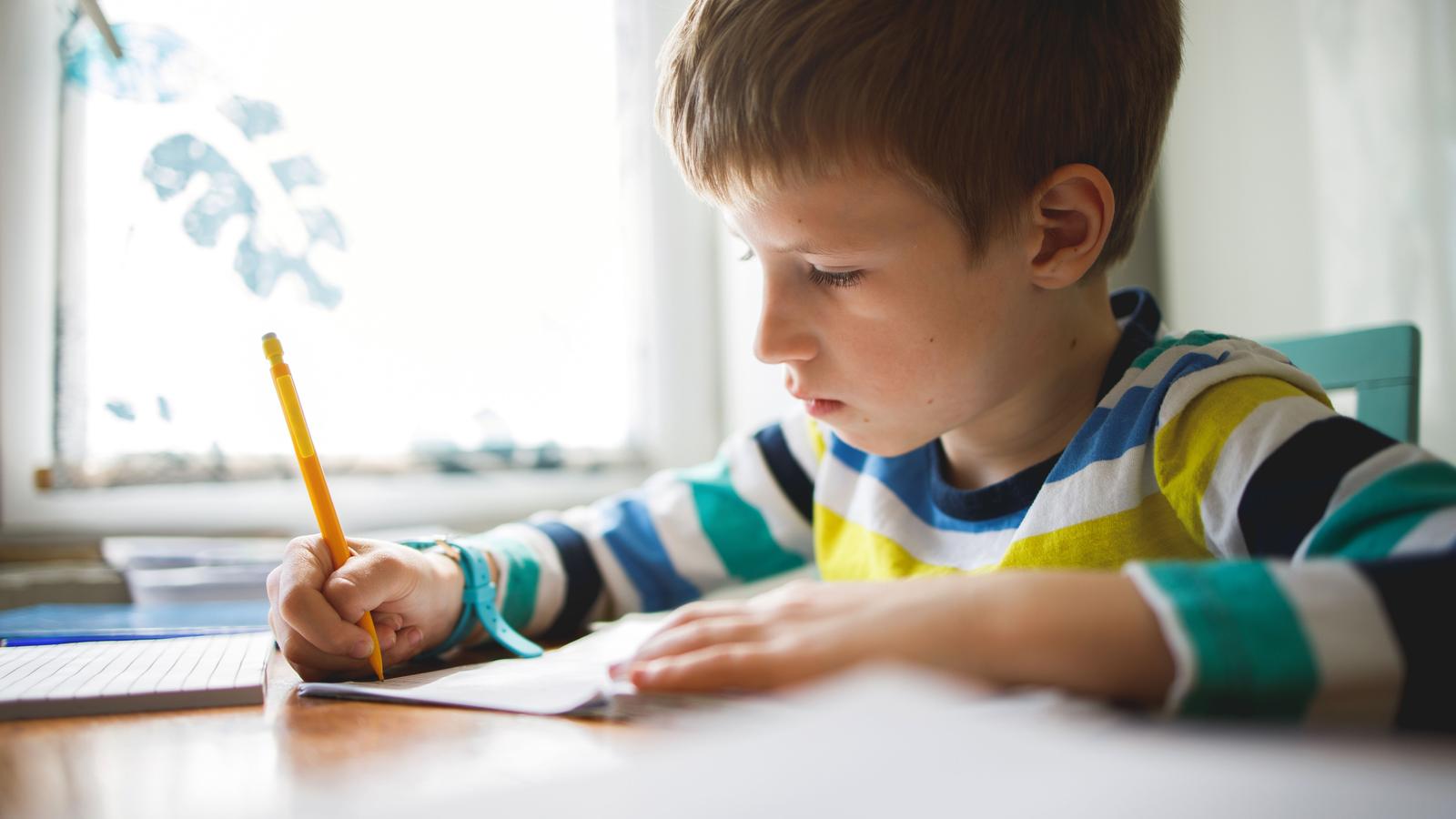 Ein Kind macht Hausaufgaben und schreibt einen Text.
