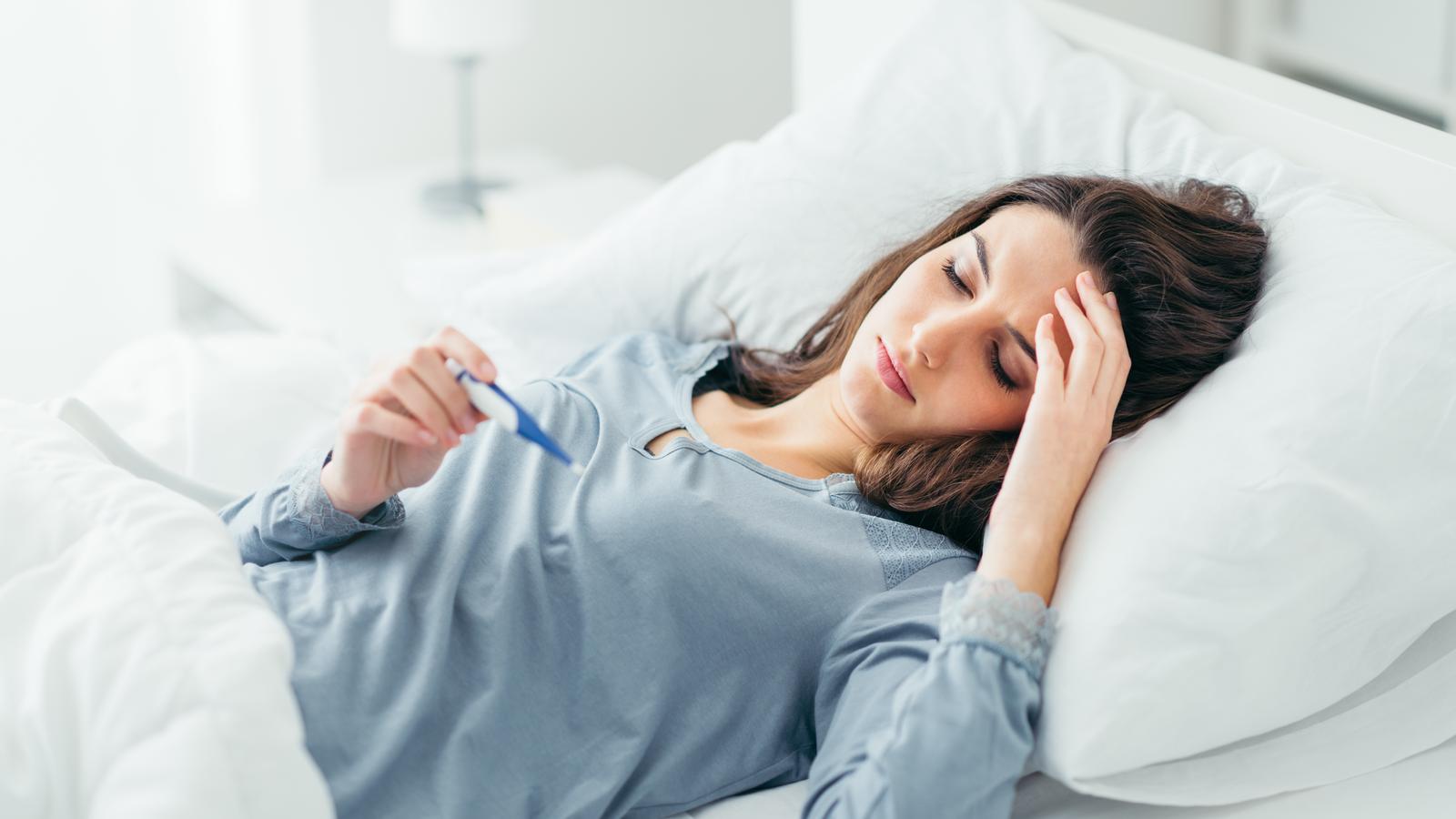 Kranke Frau liegt neben Medikamenten im Bett