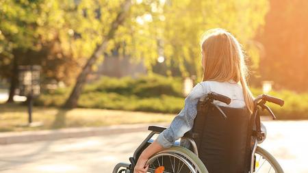 Junge Frau mit Querschnittslähmung sitzt im Rollstuhl