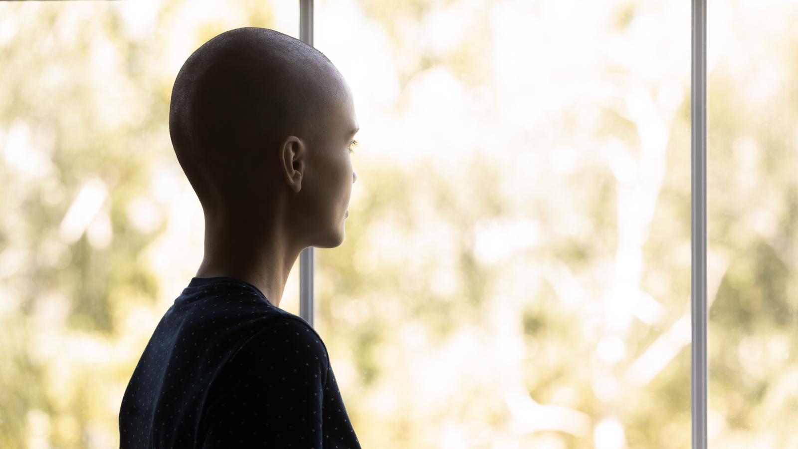 Krebskranke Frau schaut nachdenklich aus dem Fenster