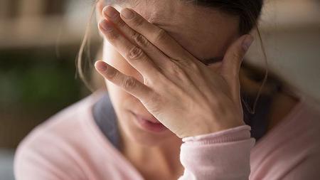 Frau mit Drehschwindel greift sich an den Kopf