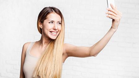 Frau macht ein Selfie mit ihrem Handy. 