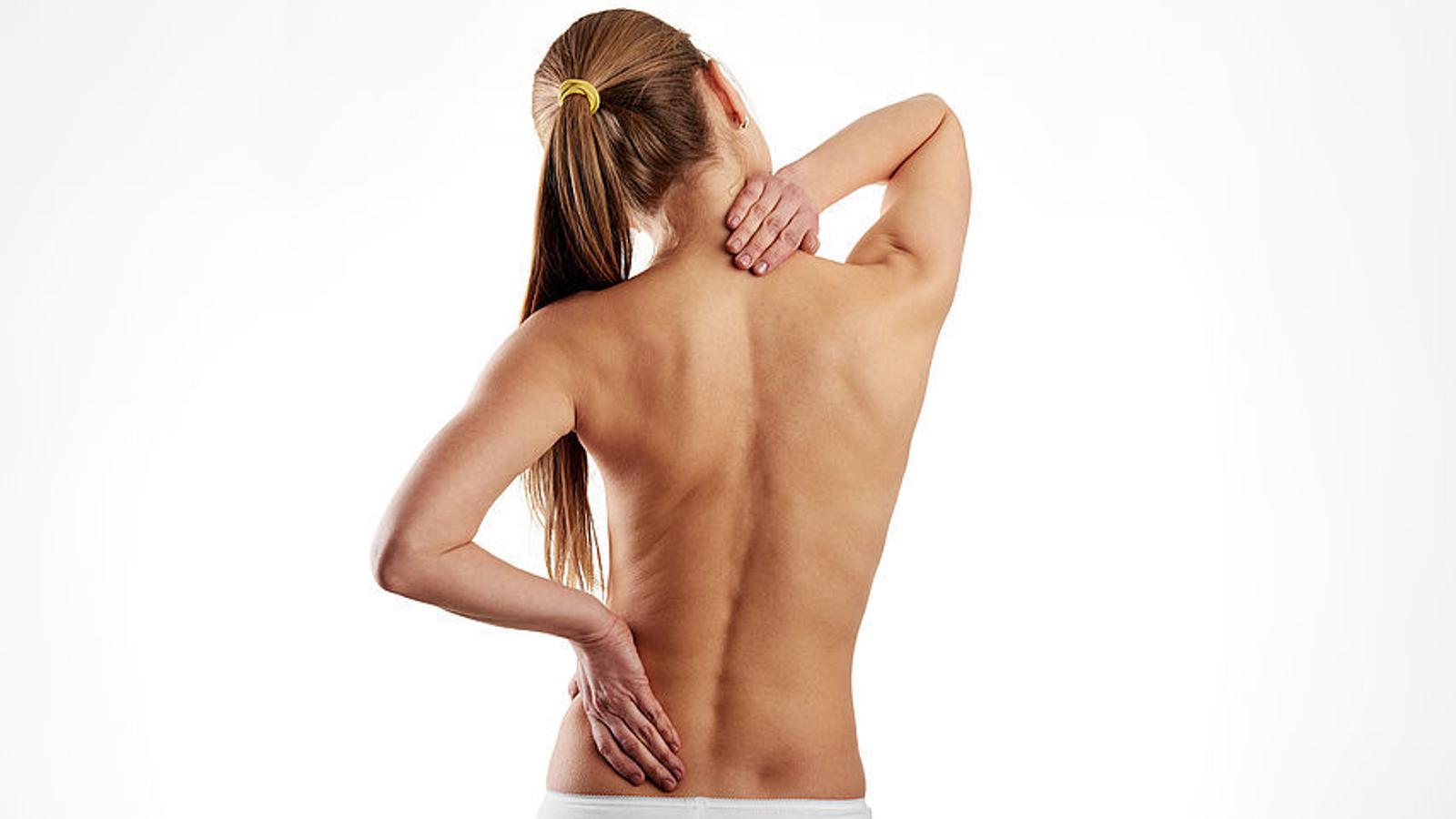 Frau mit Wirbelsäulenverkrümmung greift sich auf den schmerzenden Rücken.. 