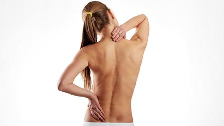 Frau mit Wirbelsäulenverkrümmung greift sich auf den schmerzenden Rücken.. 