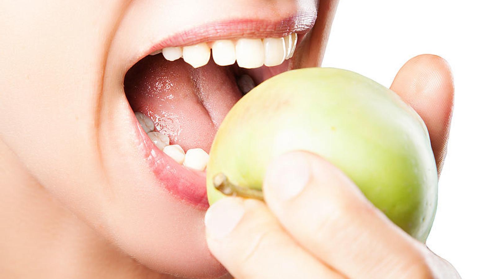 Frau ohne Zahnfleischbluten beißt kräftig in einen Apfel