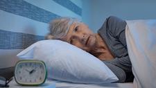 Ältere Frau liegt im Bett und kann nicht schlafen