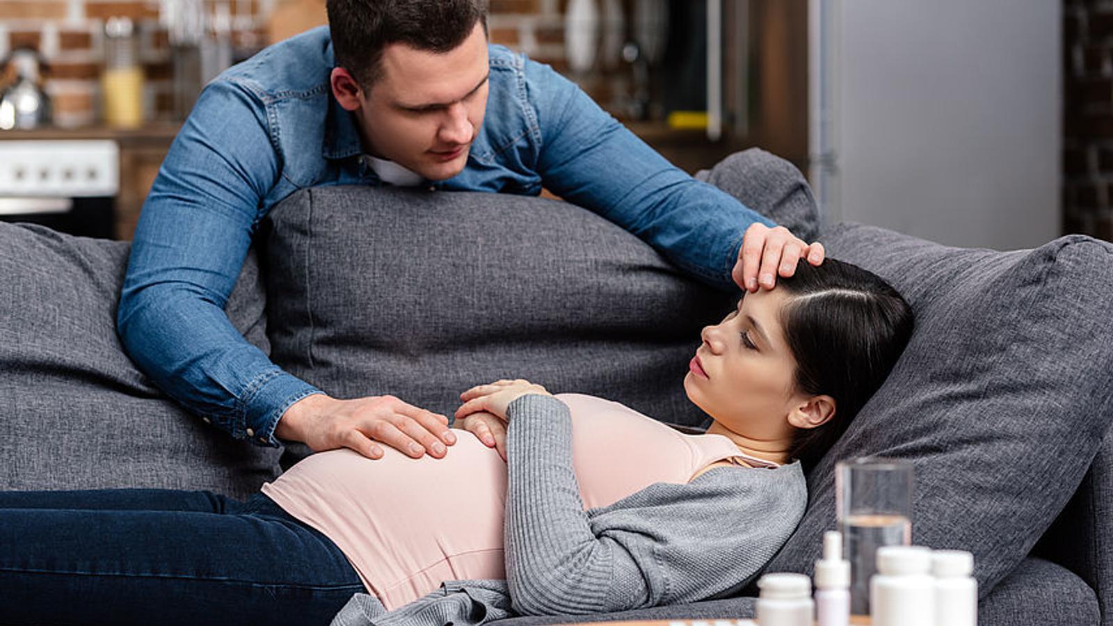 Mann kümmert sich um seine schwangere Frau, die erkältet ist