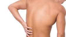 Mann greift sich auf schmerzenden Rücken - ein Wärmegürtel könnte helfen. 