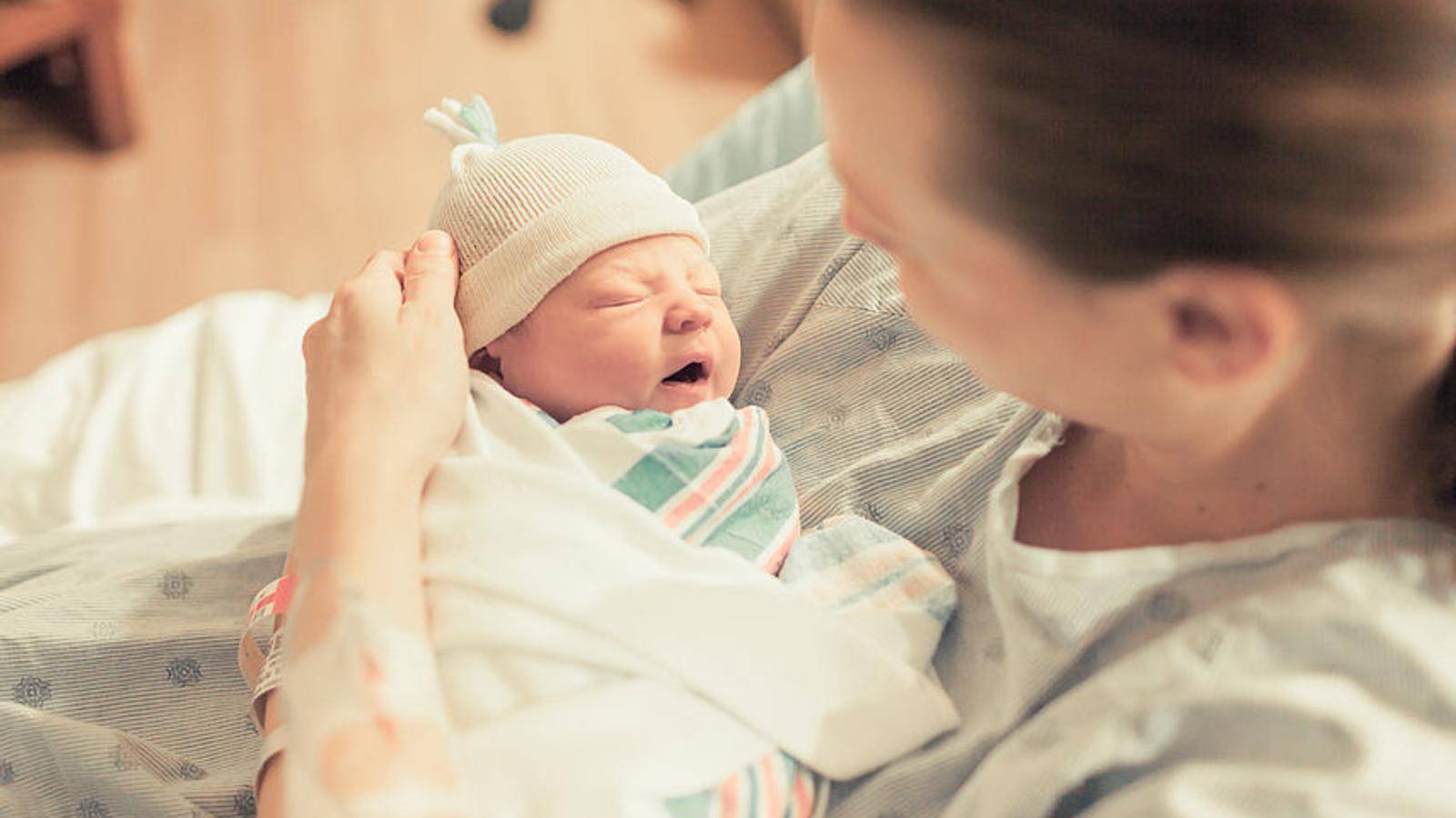 Frau hält kurz nach der Geburt ihr Baby in der Hand