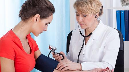 Doktor misst Frau den Blutdruck